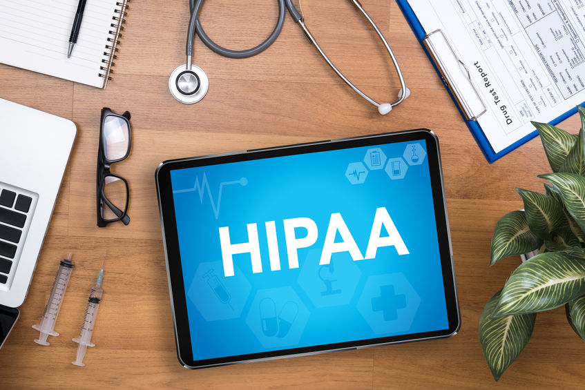 Tabletop with medical supplies and tablet with HIPAA lettering on blue background