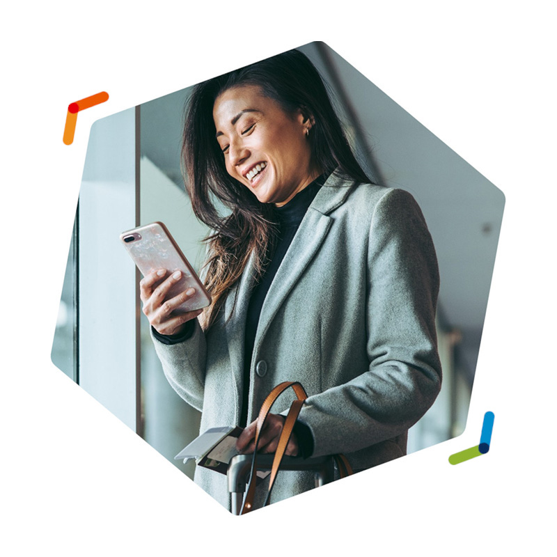 Traveling businesswoman looking at smartphone and laughing