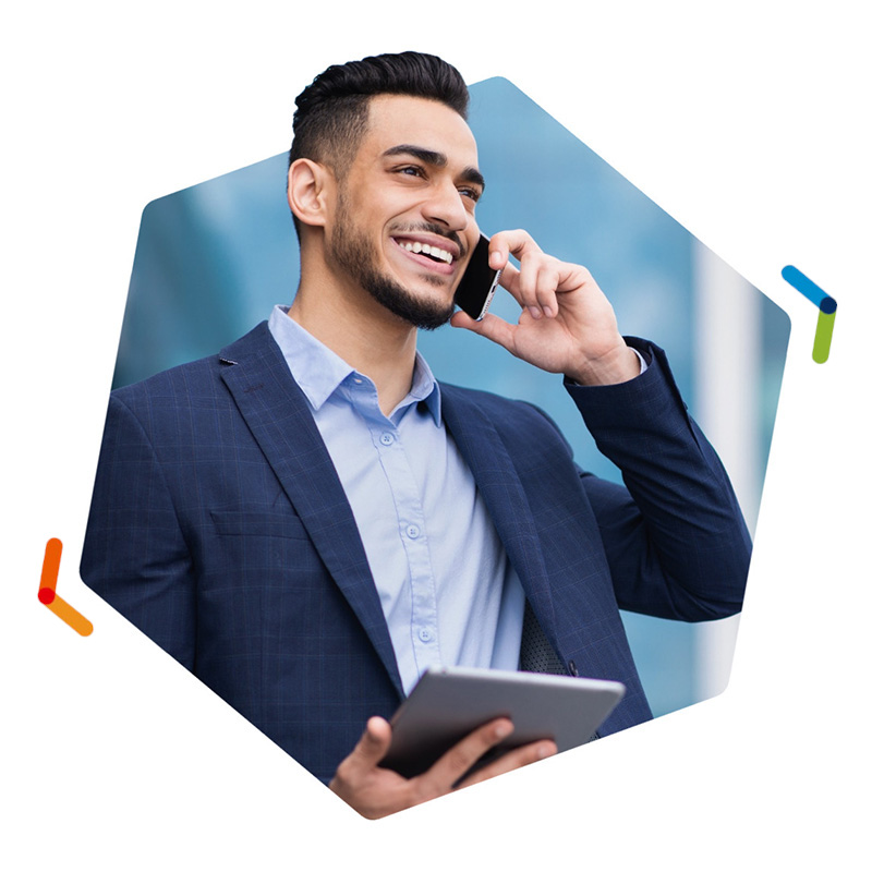 Smiling man holding tablet and talking on smartphone