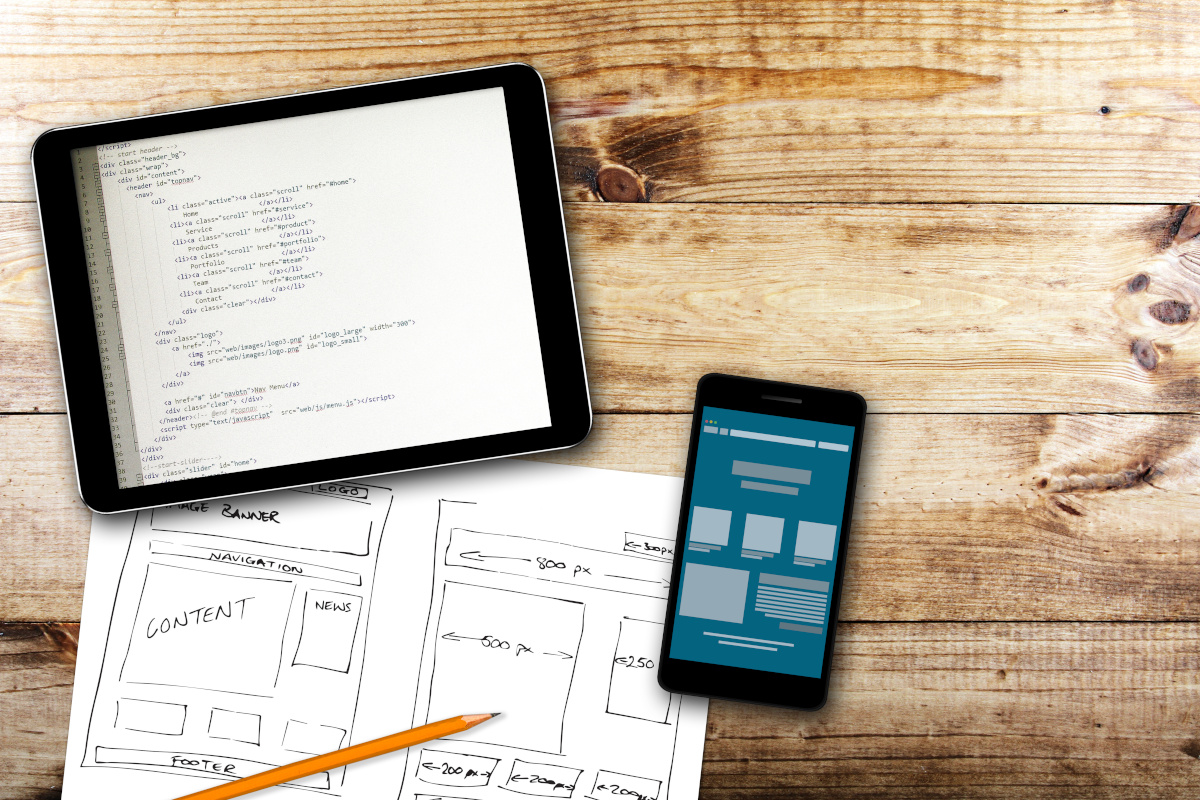 A tablet, a phone, and a paper on a desk being used to optimize a website